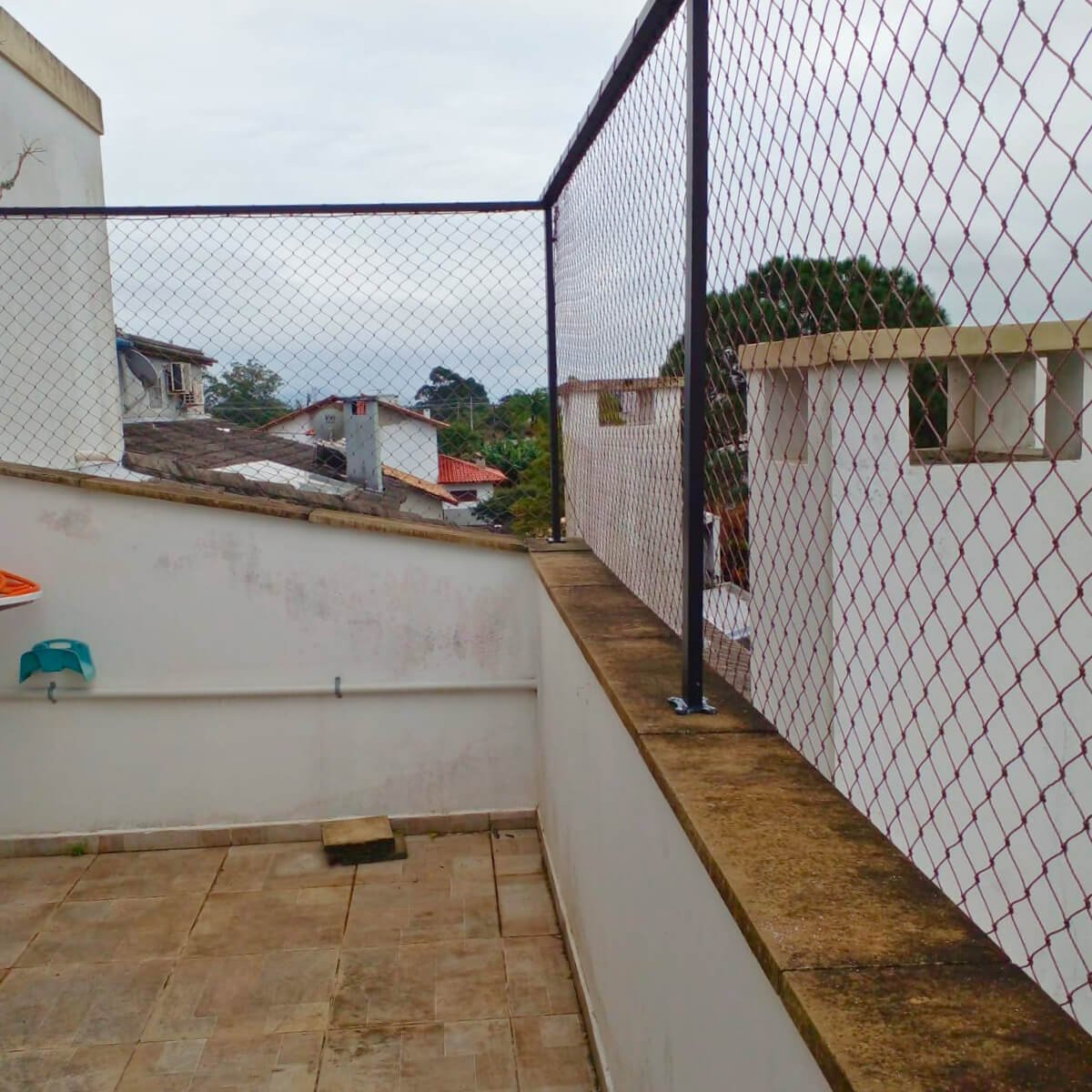 Terraço com mureta baixa e estrutura metálica preta adicionada para fixação da rede.