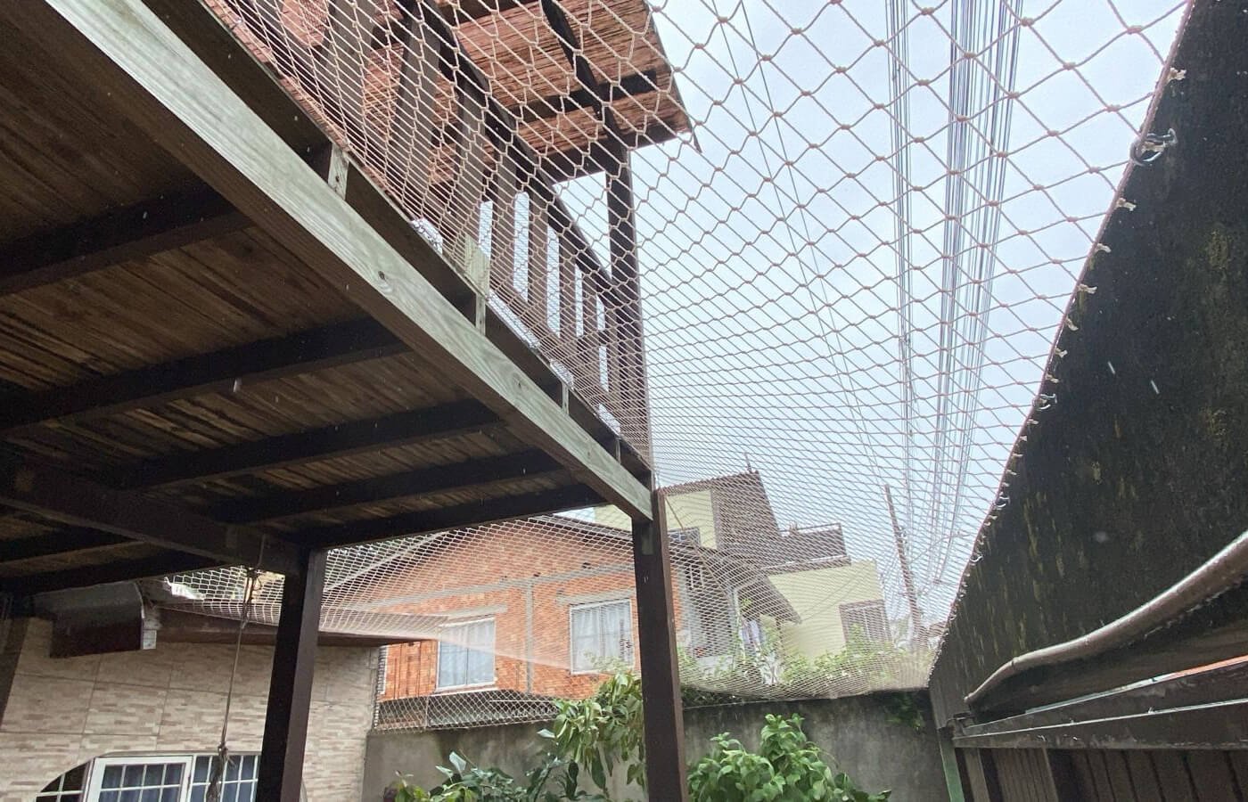 Lateral de um deck de madeira em altura protegido por rede.