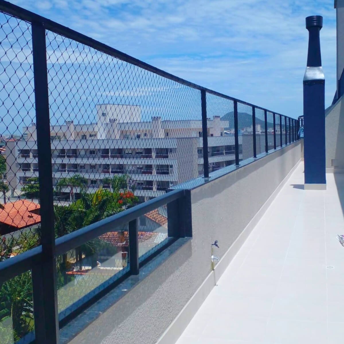 Extensão de sacada protegida por rede de segurança instalada em estrutura de metal preta.